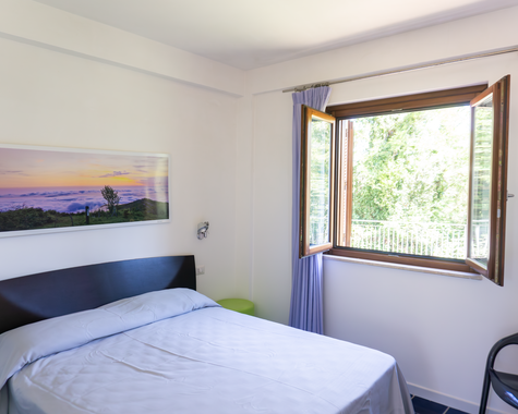 Schlafzimmer mit Doppelbett und Fensterblick