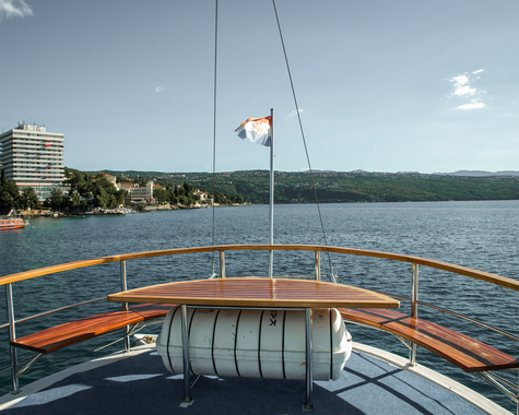 Aussicht vom Vorderdeck eines Schiffes über das ruhige Meer und die Küstenlandschaft.