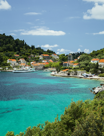 Türkisfarbene Badebucht mit kristallklarem Wasser und Häusern an der Küste.
