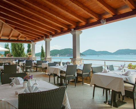 Überdachte Restaurantterrasse mit Meerblick und gedeckten Tischen direkt an der Küste.