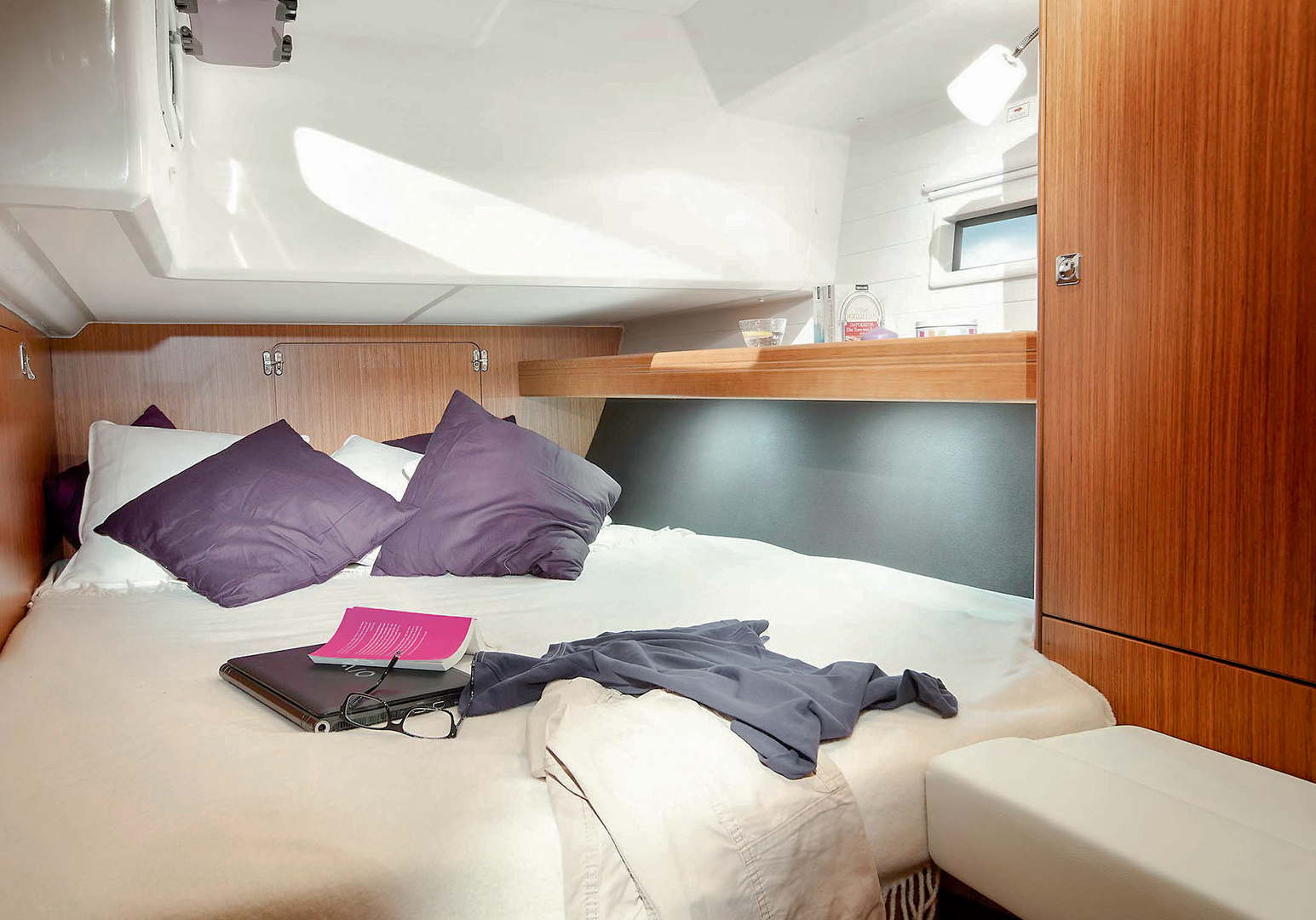 Gemütliche Schlafkabine auf einer Segelyacht mit Doppelbett und Stauraum aus Holz.