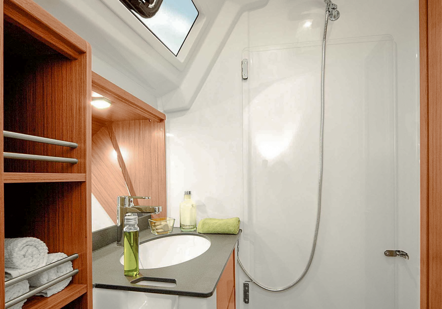 Kompaktes Badezimmer an Bord einer Segelyacht mit Waschbecken, Dusche und WC.
