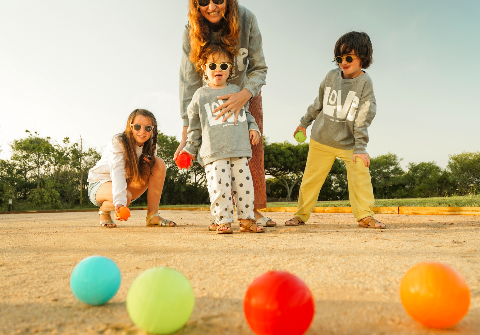 Kinder spielen gemeinsam im Freien mit bunten Bällen auf einer Wiese.