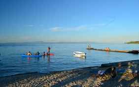 Am flachen Strand spielen die Kinder, die Großen springen vom Badesteg - Kajaks und Tretboot stehen kostenfrei bereit.