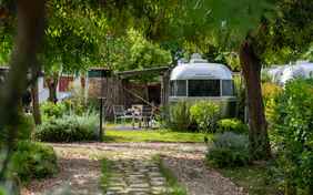 Der Airstream von außen mit Markise und einer Sitzgelegenheit.