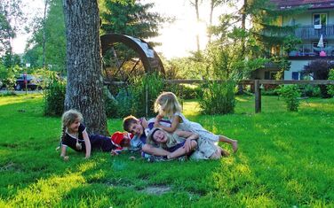 Spielende Kinder In einem Garten und im Hintergrund Appartements 
