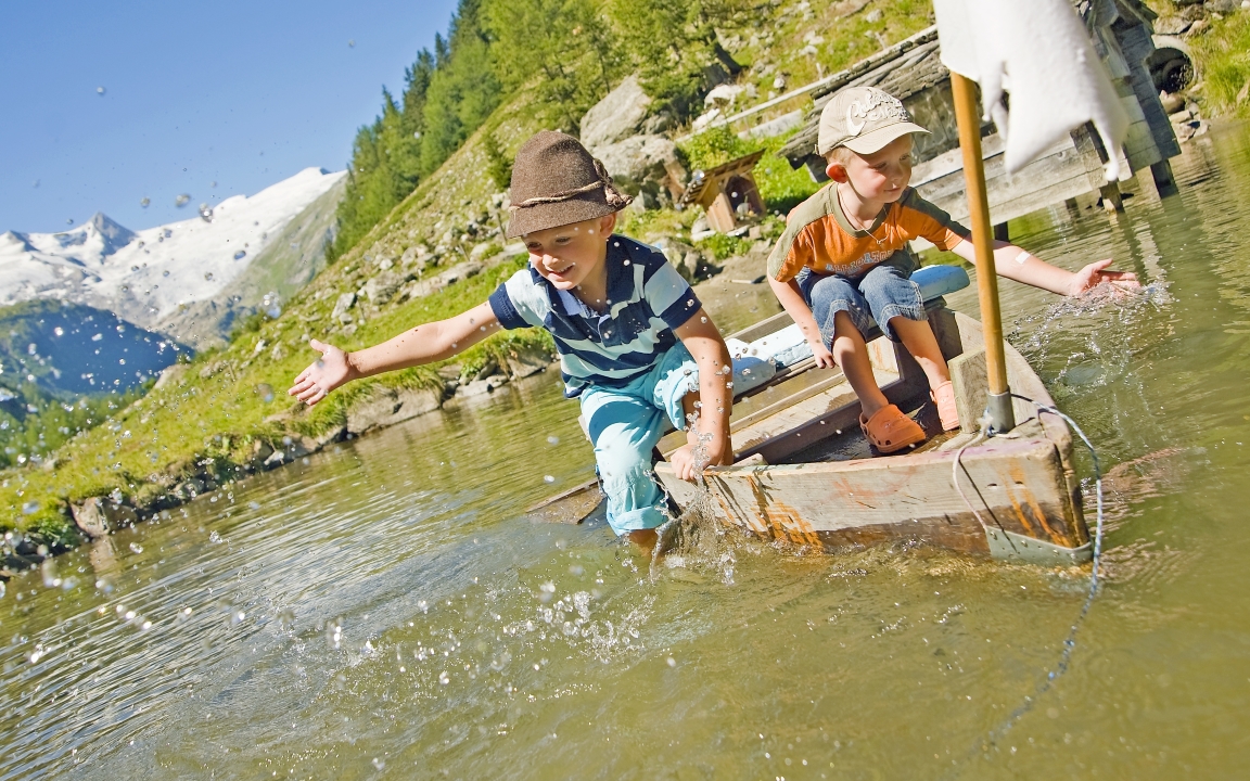 zwei Jungs spielen auf einem selbst gebautem Boot auf dem Wasser 